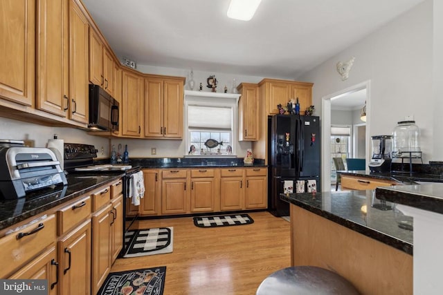 kitchen with light wood-type flooring, black appliances, and dark stone countertops