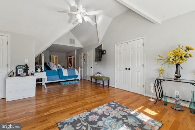 interior space with visible vents, ceiling fan, wood finished floors, high vaulted ceiling, and baseboards