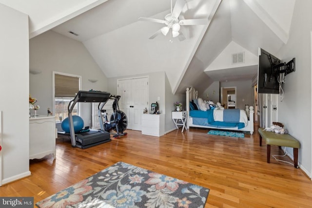 exercise area with visible vents, hardwood / wood-style floors, ceiling fan, high vaulted ceiling, and baseboards