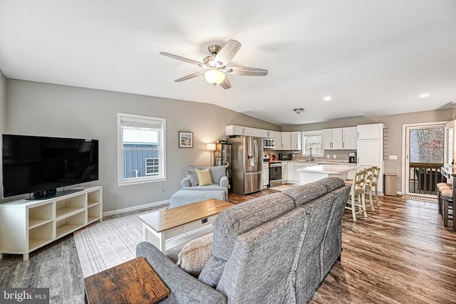 living area featuring lofted ceiling, recessed lighting, a ceiling fan, wood finished floors, and baseboards