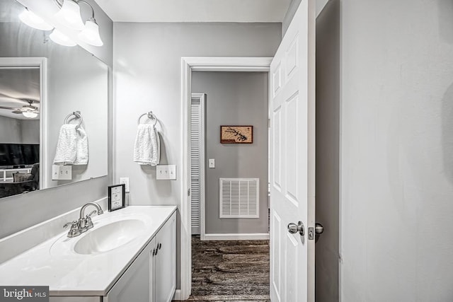 bathroom with baseboards, visible vents, ceiling fan, wood finished floors, and vanity