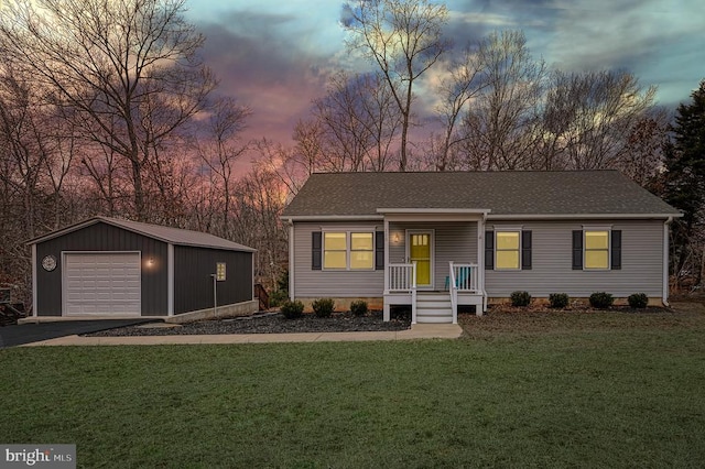 view of front of property featuring aphalt driveway, a garage, a shingled roof, an outdoor structure, and a lawn