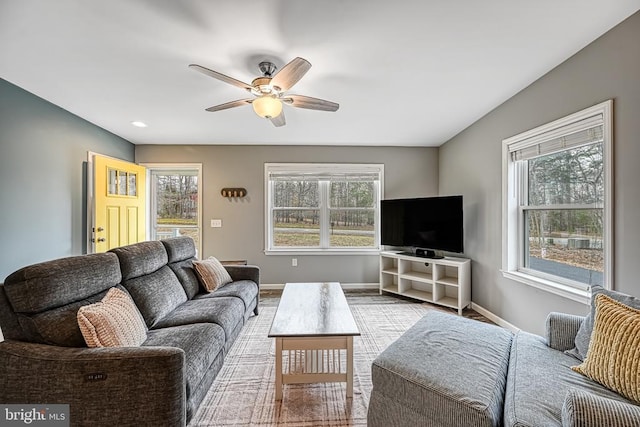 living area featuring plenty of natural light, a ceiling fan, and baseboards