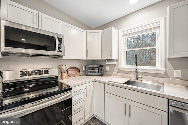 kitchen featuring stainless steel appliances, light countertops, a sink, and white cabinetry