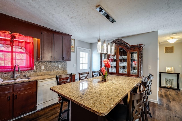 kitchen featuring sink, a center island, dark hardwood / wood-style flooring, white dishwasher, and pendant lighting