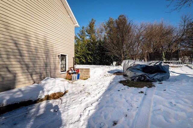 snowy yard featuring a trampoline