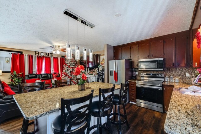 kitchen with sink, hanging light fixtures, dark hardwood / wood-style floors, stainless steel appliances, and backsplash