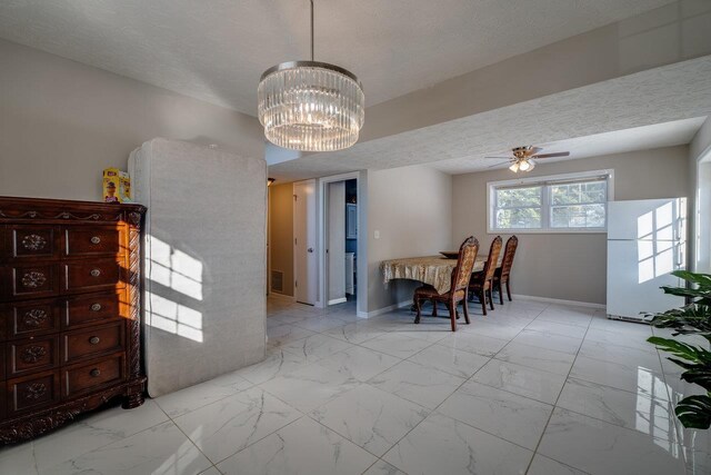 dining room featuring ceiling fan with notable chandelier and a textured ceiling