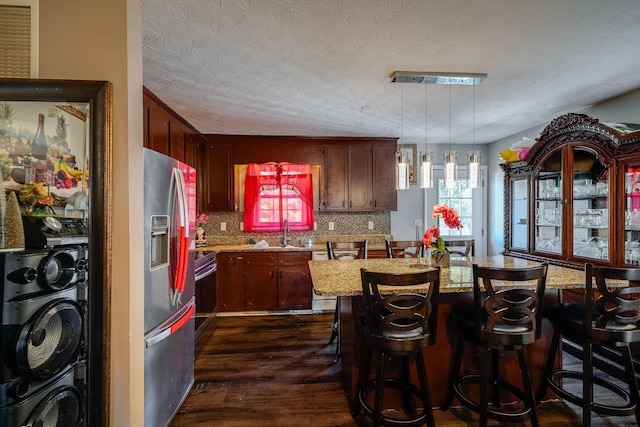 kitchen featuring sink, dark hardwood / wood-style flooring, pendant lighting, stainless steel appliances, and backsplash