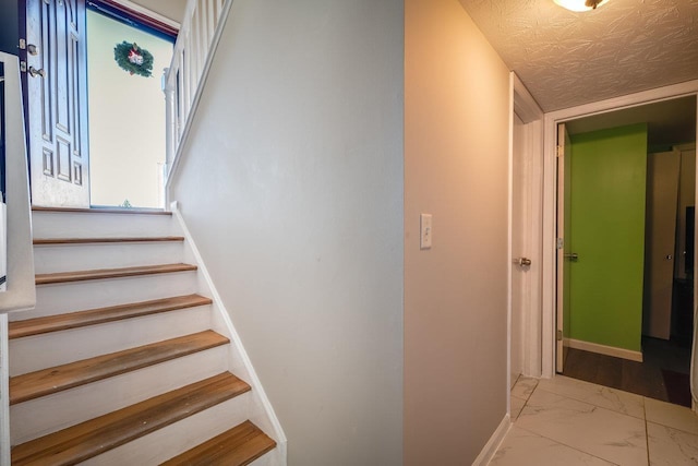 stairs featuring a textured ceiling