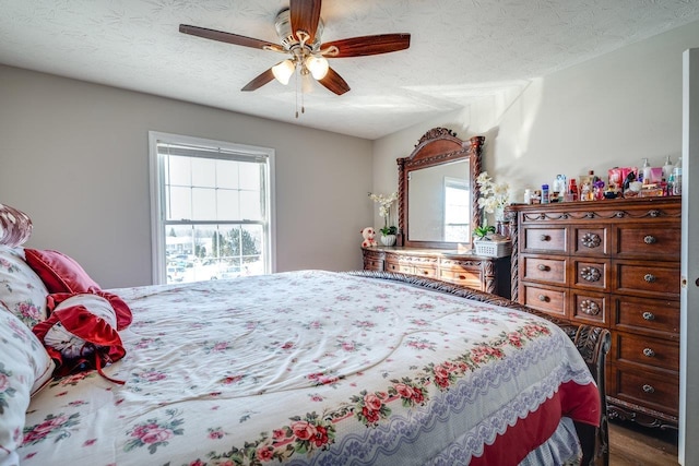 bedroom with ceiling fan, hardwood / wood-style floors, and a textured ceiling