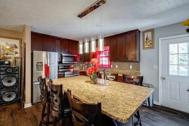 kitchen featuring pendant lighting, appliances with stainless steel finishes, dark hardwood / wood-style flooring, and a center island