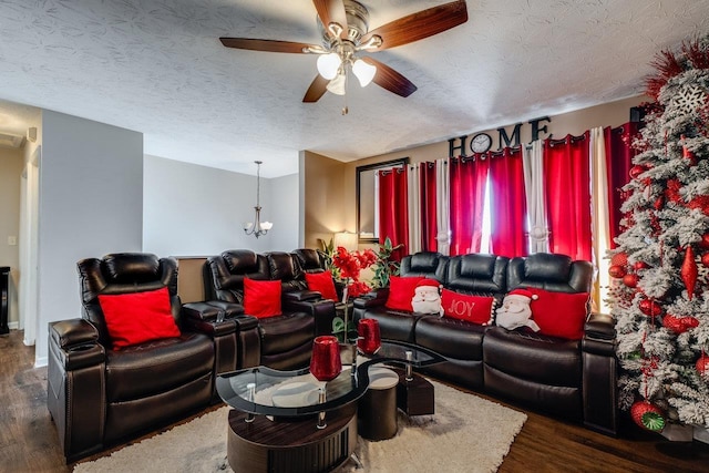 cinema with dark hardwood / wood-style floors, ceiling fan with notable chandelier, and a textured ceiling