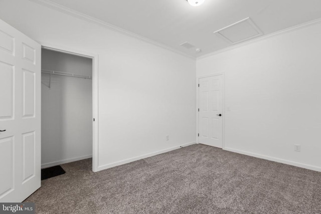 unfurnished bedroom with a closet, baseboards, attic access, carpet floors, and ornamental molding