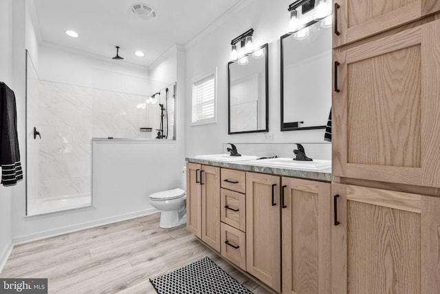 bathroom featuring crown molding, toilet, a sink, and tiled shower
