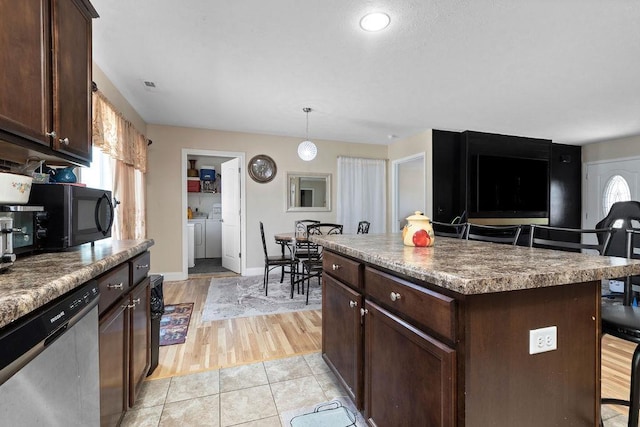 kitchen with washer and clothes dryer, dark brown cabinets, black microwave, pendant lighting, and stainless steel dishwasher