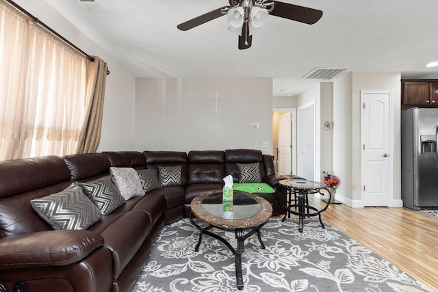 living area with light wood-style flooring, a ceiling fan, visible vents, and baseboards