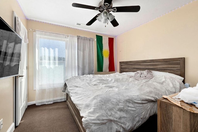 carpeted bedroom with visible vents, multiple windows, a ceiling fan, and baseboards