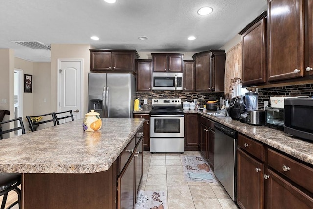 kitchen with visible vents, stainless steel appliances, backsplash, and a kitchen breakfast bar