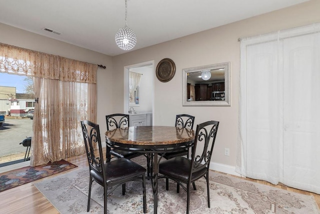 dining space with light wood finished floors, visible vents, and baseboards