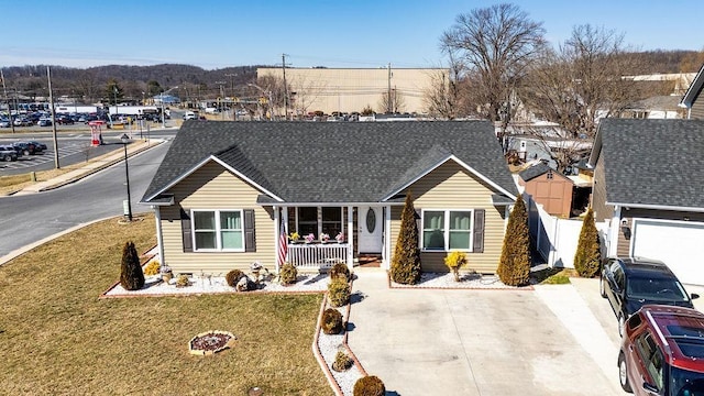 view of front of house featuring a shingled roof, a front lawn, a porch, and fence