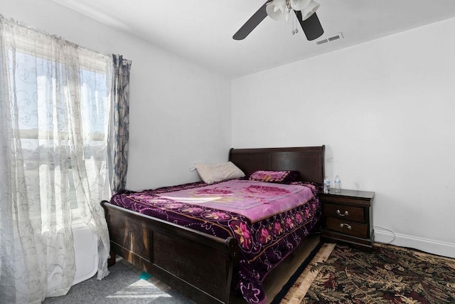 carpeted bedroom featuring a ceiling fan, visible vents, and baseboards