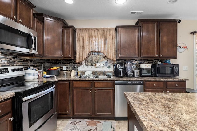 kitchen with stainless steel appliances, backsplash, a sink, and visible vents