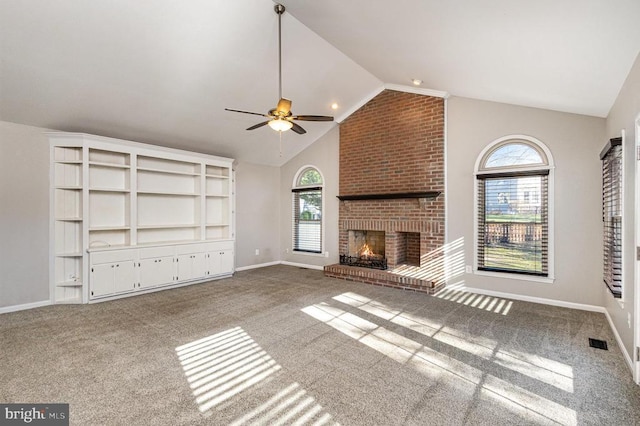 unfurnished living room featuring lofted ceiling, a fireplace, carpet flooring, and a wealth of natural light