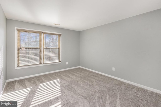 carpeted spare room featuring visible vents and baseboards