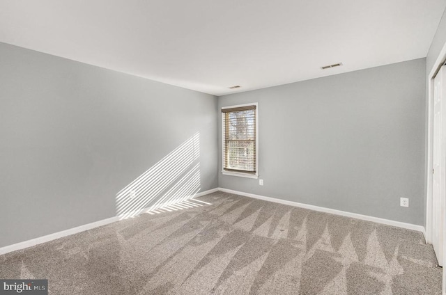 carpeted empty room with visible vents and baseboards