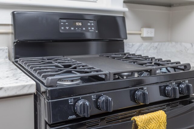 interior details featuring black range with gas stovetop and light stone counters