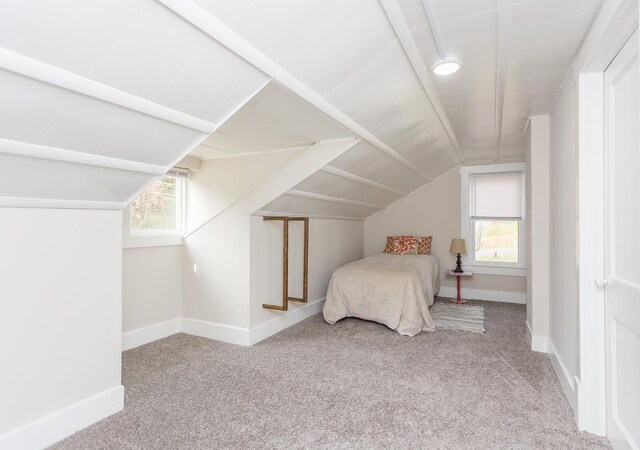 unfurnished bedroom with multiple windows, lofted ceiling, and light carpet