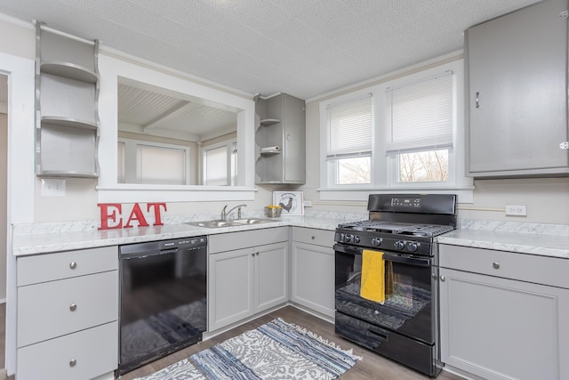 kitchen with sink, a textured ceiling, gray cabinets, hardwood / wood-style flooring, and black appliances