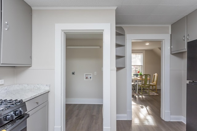 kitchen featuring light stone counters, wood-type flooring, black appliances, and gray cabinetry