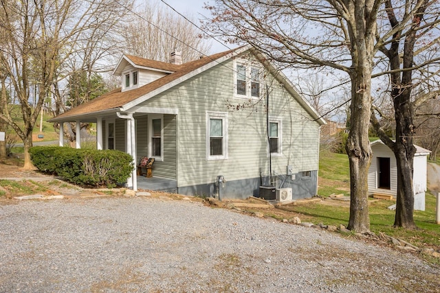 view of property exterior with covered porch and a storage unit