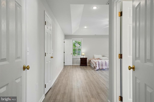 corridor with light wood-type flooring, recessed lighting, and baseboards