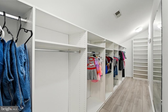 walk in closet featuring visible vents, lofted ceiling, and wood finished floors