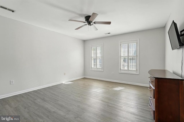 interior space featuring baseboards, ceiling fan, visible vents, and dark wood finished floors