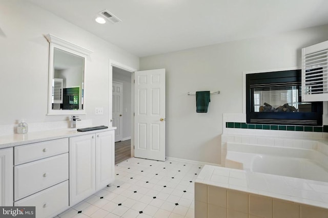 full bath featuring vanity, baseboards, a bath, and visible vents