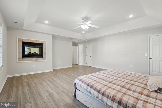 bedroom featuring a tray ceiling, recessed lighting, and wood finished floors