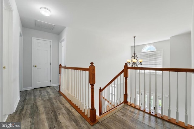 hallway with an inviting chandelier, an upstairs landing, wood finished floors, and visible vents