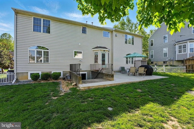 rear view of property featuring a lawn, fence private yard, and a patio area