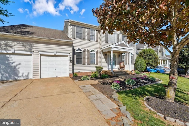 colonial inspired home featuring a garage, concrete driveway, and a front yard
