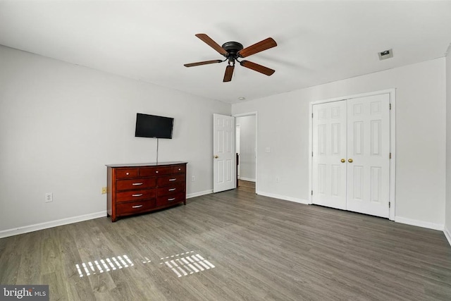 unfurnished bedroom with baseboards, visible vents, wood finished floors, and a closet