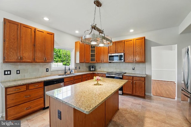 kitchen featuring brown cabinets, appliances with stainless steel finishes, a kitchen island, and a sink