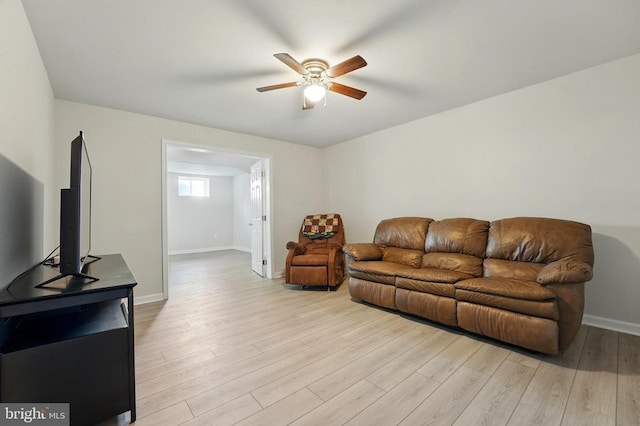 living area featuring baseboards, a ceiling fan, and light wood finished floors