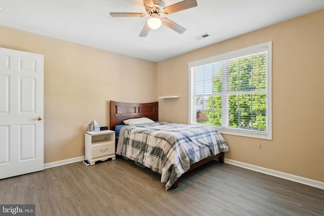 bedroom featuring ceiling fan, baseboards, visible vents, and wood finished floors