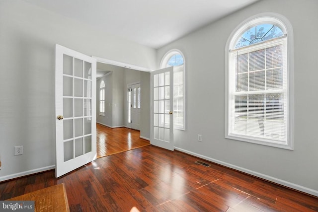 empty room with baseboards, visible vents, french doors, and wood finished floors