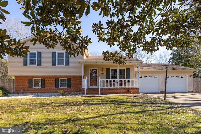 tri-level home with brick siding, covered porch, an attached garage, a front yard, and driveway