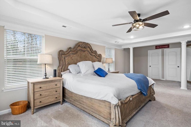 bedroom featuring light carpet, a raised ceiling, ceiling fan, and ornate columns